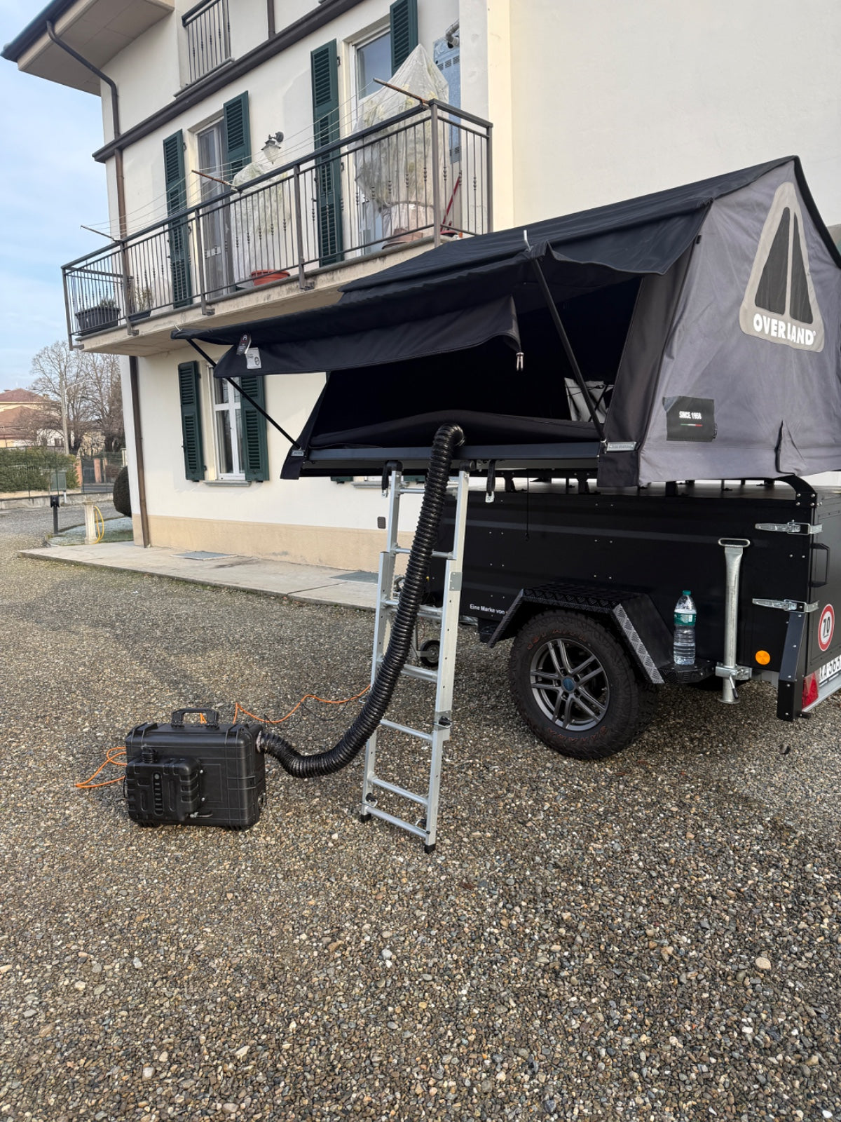 Carrello tenda con tenda da tetto aperta e tubo dell’aria calda che sale dal riscaldatore ARGOING OverlandHeat a terra
