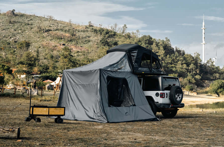 Jeep con tenda da tetto Wild Land e annesso chiuso montato sotto, al campo su un prato