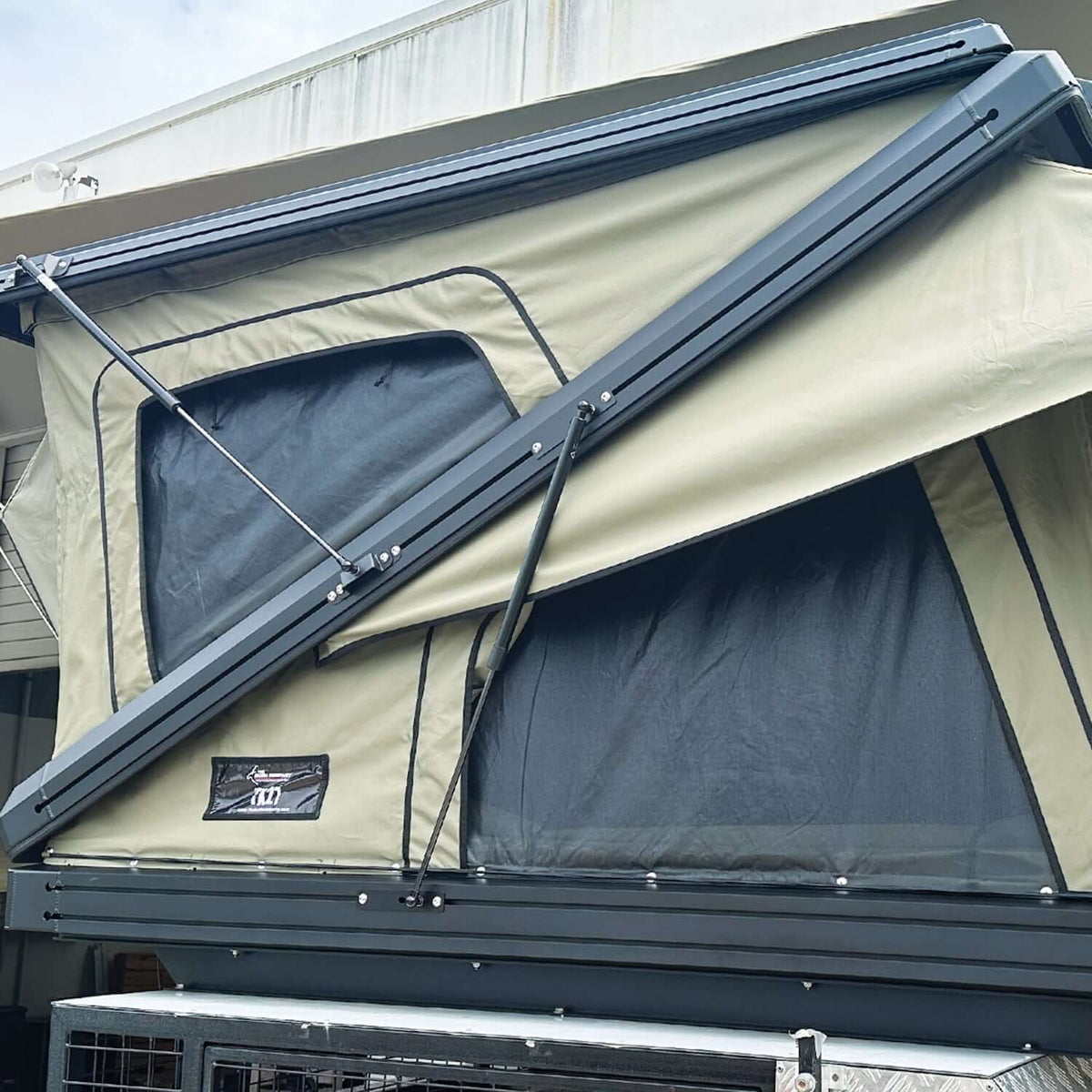The Bush Company Tenda da Tetto TX27 Hardshell Rooftop Tent with opened cover, showcasing its durable design.