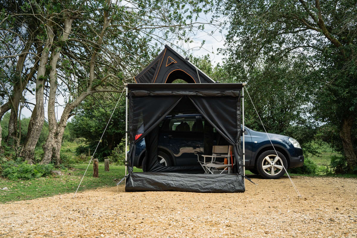 Tentbox tendalino laterale alto fino a 2.3m montato accanto a un'auto nel bosco.