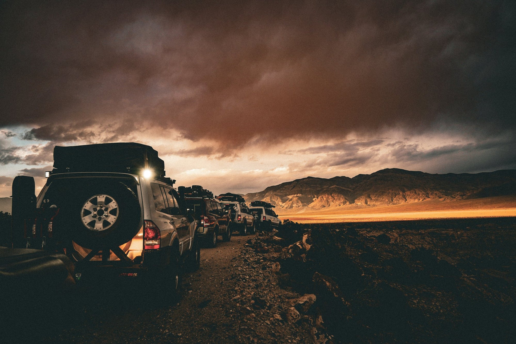 Convoglio di fuoristrada attrezzati per overlanding su pista sterrata al tramonto