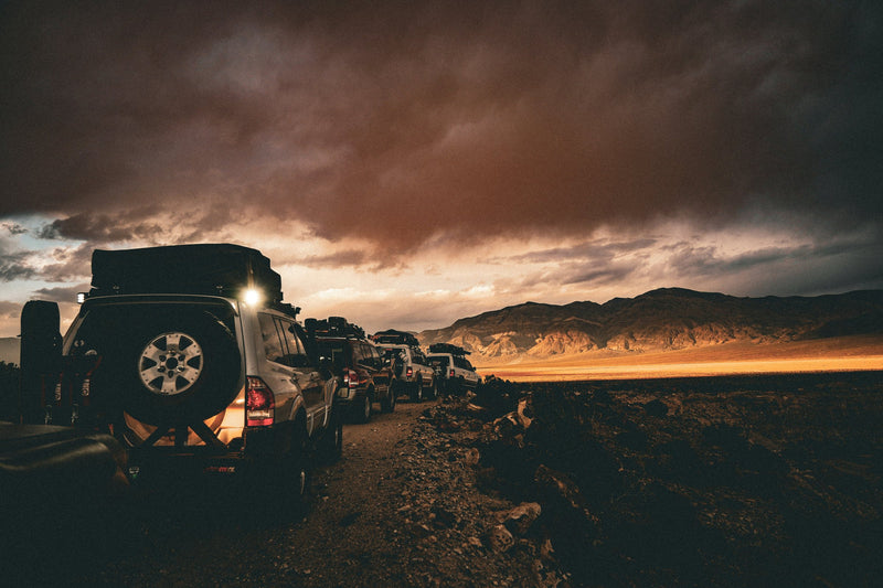 Convoglio di fuoristrada attrezzati per overlanding su pista sterrata al tramonto