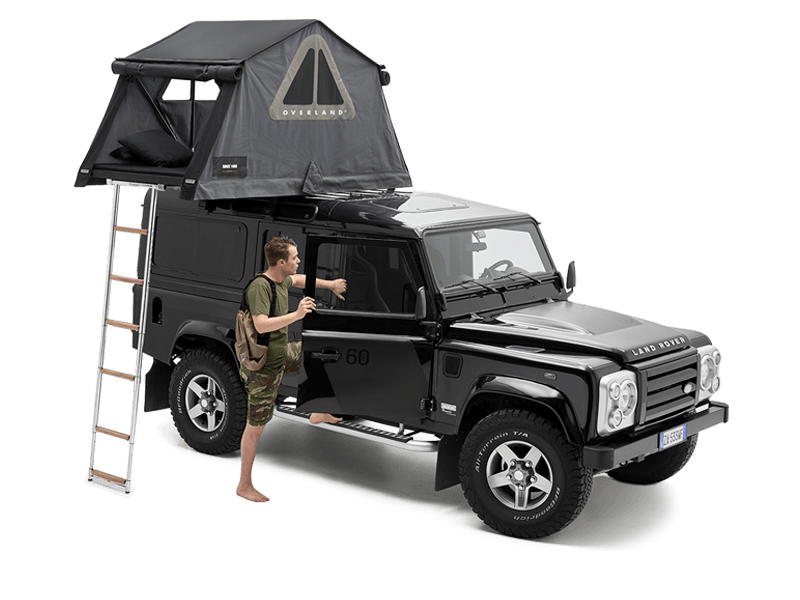 Land Rover Defender nero con tenda da tetto Autohome Overland grigia aperta e un uomo vicino alla portiera