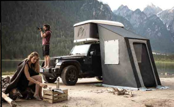 Jeep con tenda da tetto Autohome a guscio rigido e veranda chiusa in riva a un lago tra le montagne