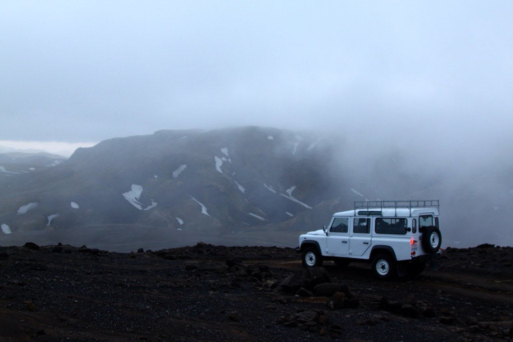 Land Rover Defender con portapacchi su un deserto di lava delle Highlands islandesi nella nebbia