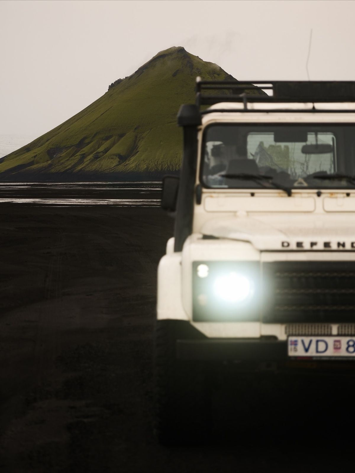 Land Rover Defender davanti al vulcano Mælifell sulla sabbia nera delle Highlands