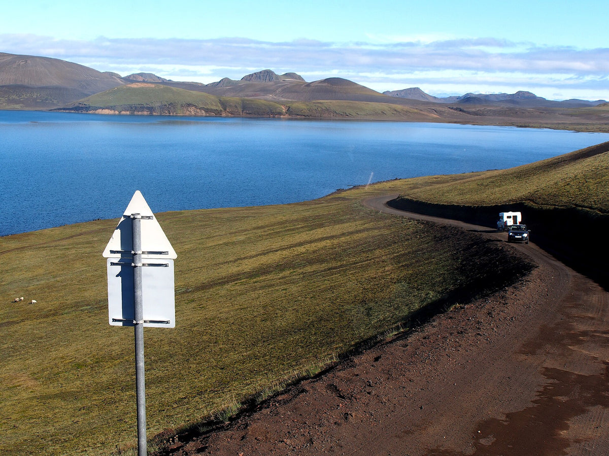 Pista sterrata lungo il lago Frostastaðavatn con un fuoristrada e un cartello stradale