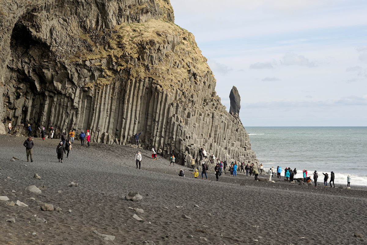 Colonne di basalto sulla spiaggia nera di Reynisfjara con visitatori e faraglioni