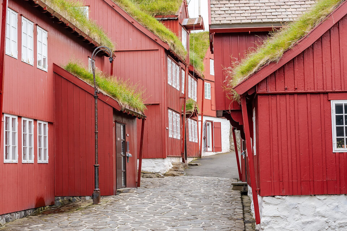 Vicolo del centro storico di Tórshavn con case di legno rosse e tetti ricoperti d’erba
