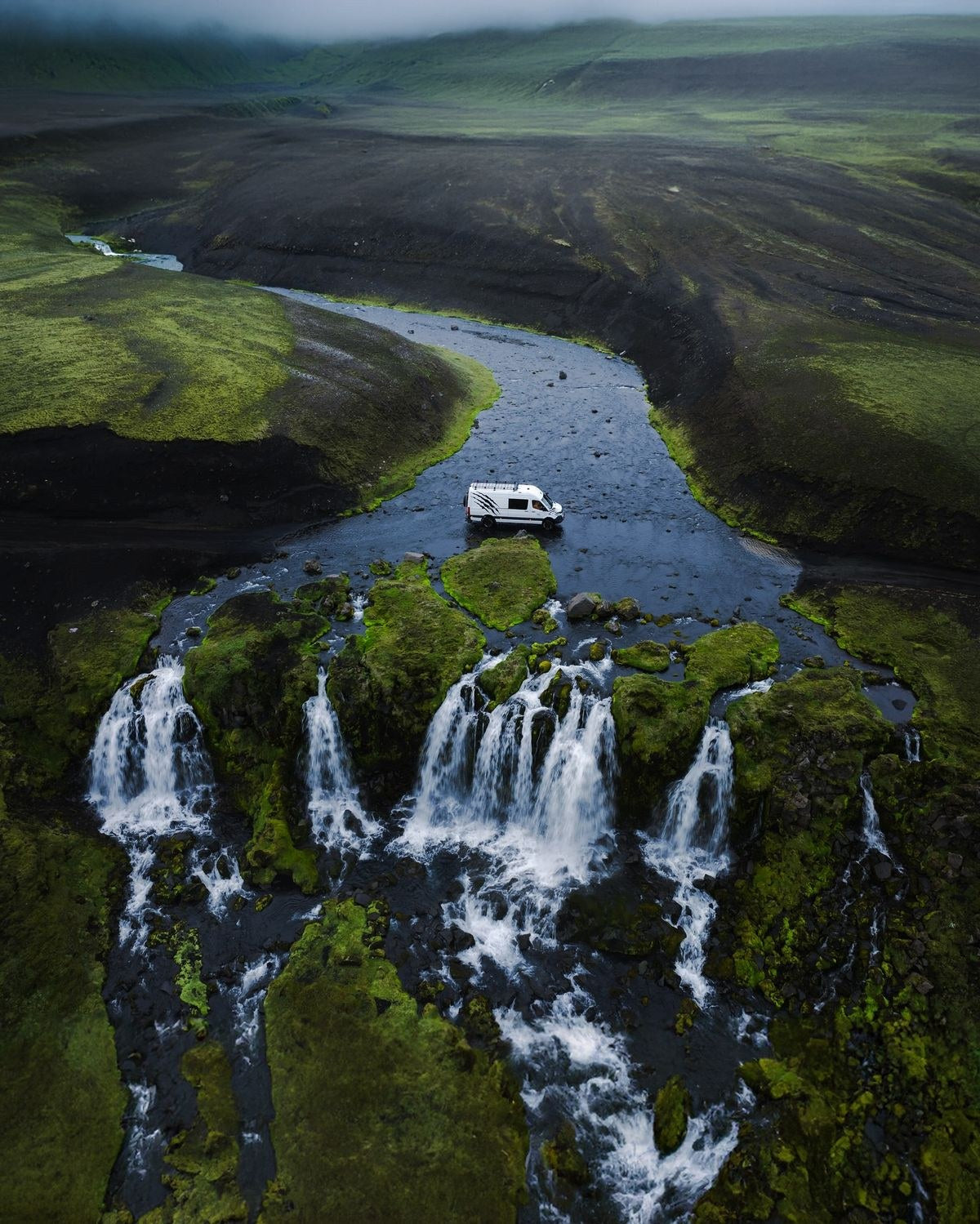 Van 4x4 bianco che attraversa un torrente sopra una cascata nelle Highlands