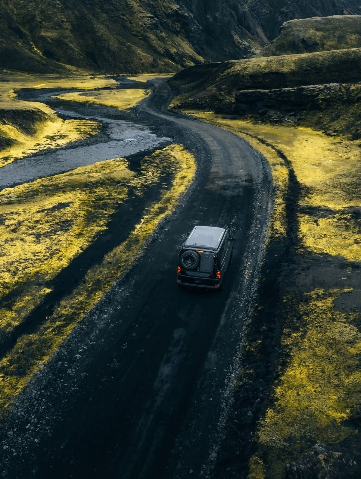 Van nero su una pista di sabbia nera tra il muschio nelle Highlands islandesi
