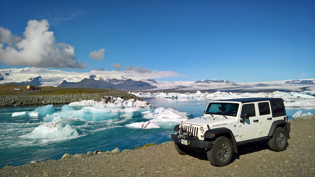 Jeep Wrangler Rubicon parcheggiato sulla riva della laguna glaciale di Jökulsárlón con iceberg e ghiacciaio